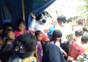 Wakil Kepala Sat Lantas Polres Metro Bekasi, Kompol Sri Supadmi saat memberikan bingkisan berupa makanan ringan dan susu kepada anak-anak yang berada di tenda pengungsian di Kp. Kerangkeng, Desa Buni Bakti, Kecamatan Babelan, Senin (06/01).