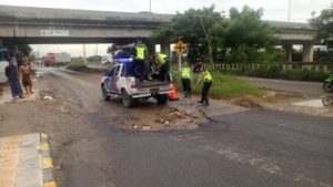 Anggota Unit Keamanan dan Keselamatan Satuan Lantas Polres Metro Bekasi saat mengurug lubang di Jalur Inspeksi Kalimalang ruas Tegal Gede – Cibitung tepatnya di Kp. Pasir Limus, Desa Wangun Harja, Kecamatan Cikarang Utara, Jum’at (10/01) pagi.