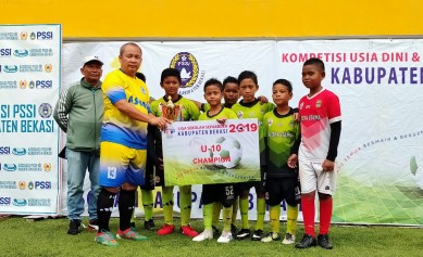 Ketua PSSI Kabupaten Bekasi, Hamun Sutisna saat memberikan trofi untuk juara pertama Kelompok Umur U10, yakni SSB Putera Utama A, Minggu (09/02).