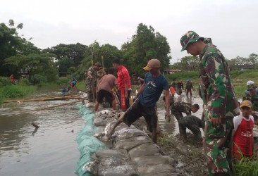 anggota Koramil 04/Babelan, aparatur kecamatan, aparatur desa, karang taruna, LPM dan warga bahu membahu memperbaiki tanggul yang jebol di RT 22/04 Desa Kedung Pengawas, Kecamatan Babelan, Jum'at (28/02).