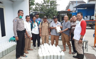 Kepala Desa Jatireja, Suwandi (ketiga dari kiri) saat melakukan pembagian cairan disinfektan kepada warga.