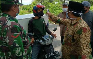 Kegiatan pengecekan suhu, pembagian masker dan pembatasan penumpang kendaraan bermotor oleh aparatur Desa Karangmekar, Kecamatan Kedungwaringin