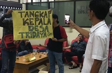 Warga membentangkan tulisan 'Tangkap Kepala Desa Tridayasakti' saat memberikan aduan tentang pemotongan dana rutilahu, Senin (22/01) siang.