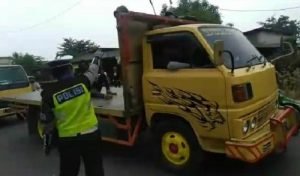 Petugas kepolisian saat menurunkan sejumlah pemudik yang kedapatan mengunggani truk di pos check point Kedungwaringin, Selasa (28/04).