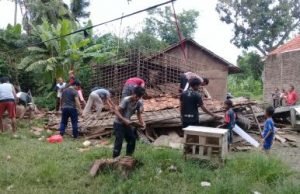 Warga setempat saat membersihkan puing bangunan rumah milik Samsudin yang ambruk pada Sabtu (20/01) kemarin.