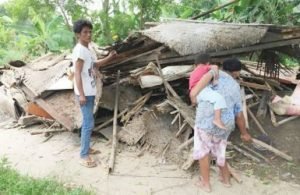 Samsudin (36) beserta istri dan anaknya meratapi sisa-sisa puing bangunan rumahny yang ambruk tersapu angin kencang, Sabtu (20/01) siang.