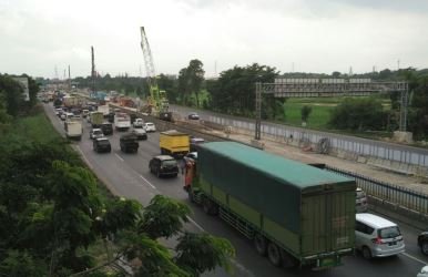 Terpantau, truk yang membawa peti kemas serta truk gandeng masuk memadati tol Jakarta Cikampek di tengah melintasnya kendaraan pribadi, Jum'at (22/12) siang.
