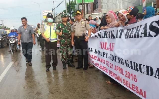 Anggota Polsek Cikarang Barat dan Koramil Cibitung saat melakukan pengamanan aksi perempuan dan Ibu rumah tangga yang melakukan aksi unjuk rasa menuntut dihentikannya produksi PT. Gunung Garuda di Kecamatan Cikarang Barat, Kamis (21/04).