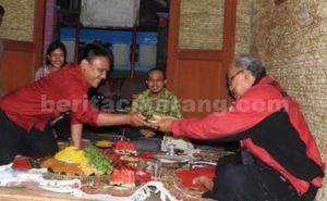 Ketua DPC GMNI Bekasi, Halason Afrizal memberikan potongan tumpeng secara simbolis kepada Alumni GMNI, Slamet Hardani.