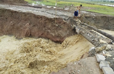 Salah seorang warga saat melintasi jembatan sementara yang terbuat dari batang pohon kapuk dan bambu, Rabu (09/01).