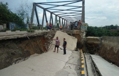 Sejumlah warga saat melihat kondisi jalan pendekat jembatan Cipamingkis yang ambruk di Desa Cibarusah Kota, Kecamatan Cibarusah yang kembali amblas, Minggu (10/03) siang.