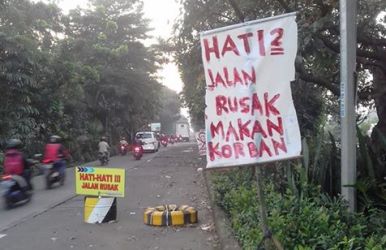 Spanduk peringatan jalan rusak yang dibuat oleh warga di Jl. Raya Inspeksi Kalimalang, Desa Gandasari, Kecamatan Cibitung. (Foto : Agoes Abdul Qadir Al-Jailani)