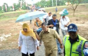 Bupati Bekasi, Neneng Hasanah Yasin dipayungi petugas usai meninjau lokasi ground breaking Stasiun KRL Telaga Murni, Senin (08/08).