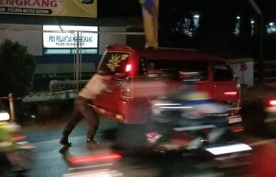 Petugas Kepolisian Sektor Cikarang Timur yang bertugas di Pos PAM Kojengkang saat mendorong angkot yang mogok di jalur pantura Kabupaten Bekasi, Kamis (30/05) malam.