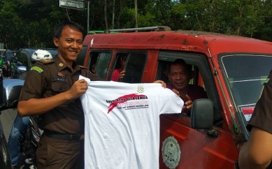 Pembagian stiker dan kaos oleh petugas Kejaksaan Negeri Kabupaten Bekasi yang dilakukan kepada para pengendara roda dua maupun roda empat di sekitar persimpangan Deltamas Desa Sukamahi Kecamatan Cikarang Pusat, Senin (09/12).