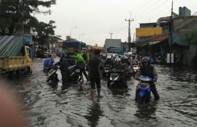 Para pengendara sepeda motor terjebak di ruas Jl. Raya Imam Bonjol, Desa Telaga Murni Kecamatan Cikarang yang diterjang banjir.