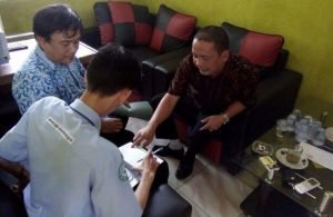 Ketua BPD Desa Cipayung, Zuli Zulkifli saat menerima kedatangan petugas BPJS untuk memeriksan keaslian Kartu Indonesia Sehat (KIS) milik warga yang salah cetak di Kantor Desa Cipayung, Kamis (04/08).
