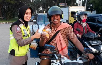 Bripda Selly saat memberikan takjil kepada pengemudi kendaraan roda dua di Traffic Light Jurong, Senin (12/06).