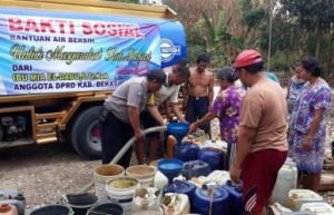 Personil Kepolisia Sektor Cibarusah saat ikut membantu warga mengisi air di penampungan, Selasa (17/09).