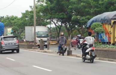 Pengendara motor saat melintasi u-turn ilegal yang dibuka tutup menggunakan sebatang bambu di depan dealer mobil Suzuki Kebayoran Jaya Indah Utama Jl. Urip Sumoharjo No.KM 59, Tanjungbaru, Cikarang Timur.