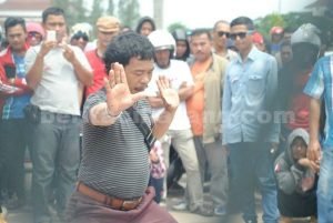 Aksi salah seorang warga yang melakukan pertunjukan Pencak SIlat Jaipongan ditengah kerumunan aksi demontrasi warga Cikarang Pusat, Selasa (12/04) kemarin.