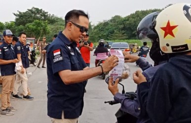 Kepala Lapas Cikarang, Kadek Anton Budiharta saat membagikan takjil dan menjelaskan tentang nilai-nilai Pancasila di selebaran yang dibagikan kepada pengendara motor di area Taman Sehati, Komplek Stadion Wibawamukti, Kamis (31/05).