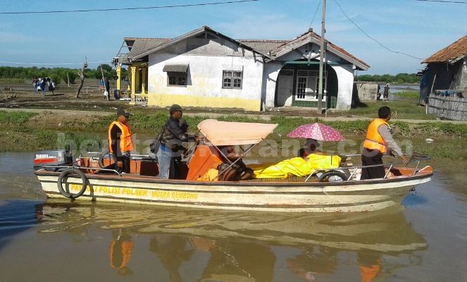 Anggota kepolisian dan warga saat mengvakuasi jenazah korban ke Mapolsek Muara Gembong menggunakan perahu, sesaat sebelum dibawa ke RSUD Cibitung sebelum dilakukan visum, Minggu (15/05)