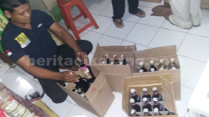 Anggota Polsek Setu saat mengamankan puluhan botol minuman keras dari warung klontong milik JLG dan DS di Desa CIleduk, Kecamatan Setu, Jum'at (22/05).