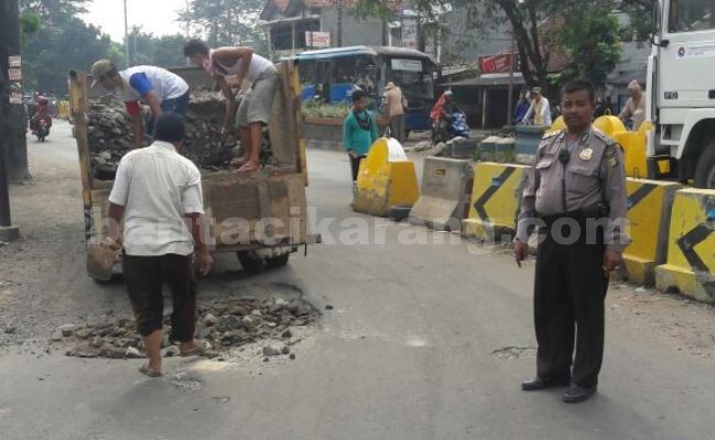 Panit Sabhara Polsek Cikarang Barat, Aiptu Nrimo saat melakukan penutupan jalan yang berlubang di Jl. Raya Arteri Cibitung, Minggu (05/06).