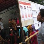 Salah seorang warga saat membaca visi dan misi Calon Gubernur dan Wakil Gubernur Jawa Barat di salah satu TPS di Kabupaten Bekasi