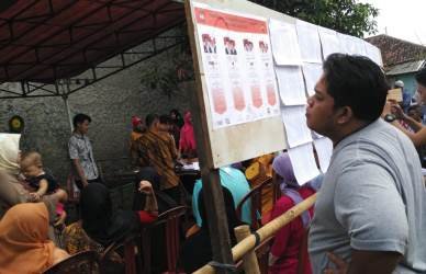 Salah seorang warga saat membaca visi dan misi Calon Gubernur dan Wakil Gubernur Jawa Barat di salah satu TPS di Kabupaten Bekasi