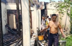 Petugas kepolisian sektor cibarusah bersama warga saat berusaha mendinginkan api di lokasi rumah yang terbakar dan mengangkut air dengan peralatan seadanya, Minggu (26/05).