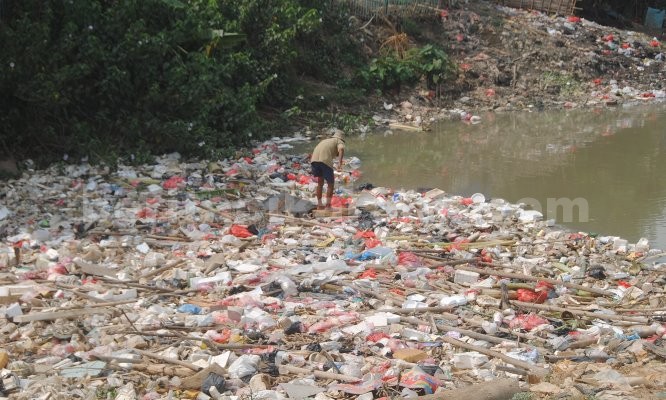 Abah (72) mencari nafkah diatas tumpukan sampah yang mengapung di kali CBL beberapa waktu lalu.