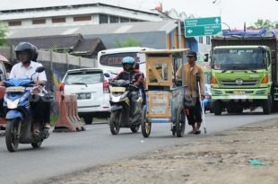 DIbantu penyangga pada kaki kirinya, Suhendar (50) tak kenal letih mendorong gerobak tahu sumedangnya di Jl. Raya Indsutri Cikarang, Sabtu (26/03).