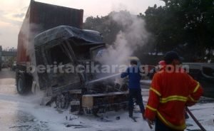 Petugas pemadam kebakaran saat mendinginkan kepala mesin truk ke 3 yang meledak akibat tabrakan beruntun di KM 18 Tol Jakarta Cikampek, Selasa (07/06) sore.