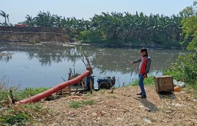 Salah seorang warga saat melihat pompa air milik petani yang digunakan untuk menyedot lahan pertanian mereka dari Kali CBL, Sabtu (06/10).