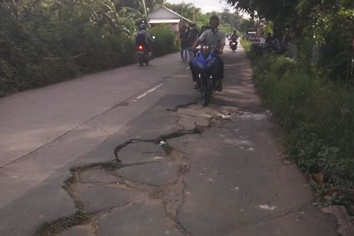 Salah seorang pemotor saat melintasi ruas jalan yang mengalami keretakan di Jl. Raya Cabangbungin, Kp. Pulo Glatik, Desa Sindangsari, Kecamatan Cabangbungin, Senin (21/12).