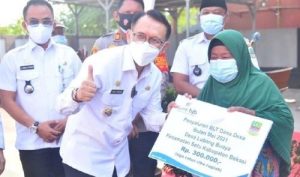 Pj Bupati Bekasi, Dani Ramdan saat menyalurkan dana BLT DD secara simbolis kepada warga di Desa Lubang Buaya, Kecamatan Setu, Rabu (28/07). Di desa ini, BLT DD disalurkan untuk 41 keluarga yang terdampak secara ekonomi oleh pandemi Covid-19 dengan nilai sebesar Rp 300.000.