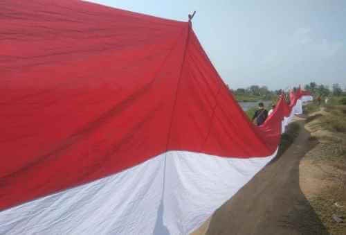 Pengibaran bendera merah putih raksasa di area Tambak Segi Tiga Emas, Desa Pantai Harapan Jaya, Kecamatan Muaragembong, Selasa (17/08)