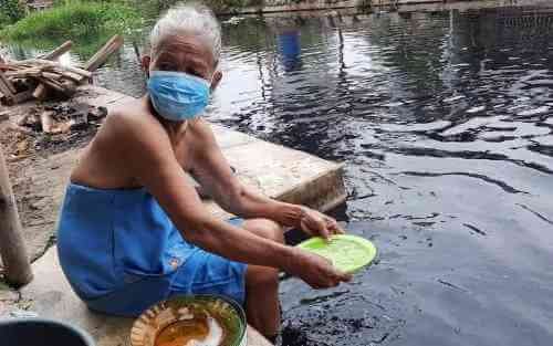Nyai (85), warga Desa Sukaraya, Kecamatan Karangbahagia saat mencuci piring di bantaran aliran sungai Cilemahabang yang hitam dan bau, Senin (06/09).