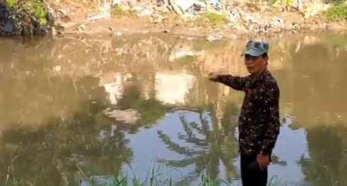 Salah seorang warga saat menunjukan lokasi penampakan buaya di aliran Kali Bekasi Desa Sukamekar, Kecamatan Sukawangi,