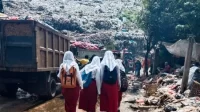 Sejumlah pelajar melintasi timbunan sampah di TPA Burangkeng yang kondisinya overload sejak tahun 2019 lalu.