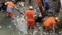 Petugas dari Unit Pelaksana Teknis Daerah (UPTD) Pengelolaan Sampah Wilayah II DLH Kabupaten Bekasi saat membersihkan sampah dari Kali Cikarang Srengser Hilir (CSH) di Desa Sukaringin, Kecamatan Sukawangi.