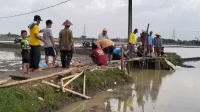Warga bersama aparatur Pemerintah Desa Karangsari secara swadaya membangun jembatan darurat di akses jalan Kampung Tengah, Desa Karangsari, Kecamatan Cikarang Timur yang putus diterjang bencana banjir.