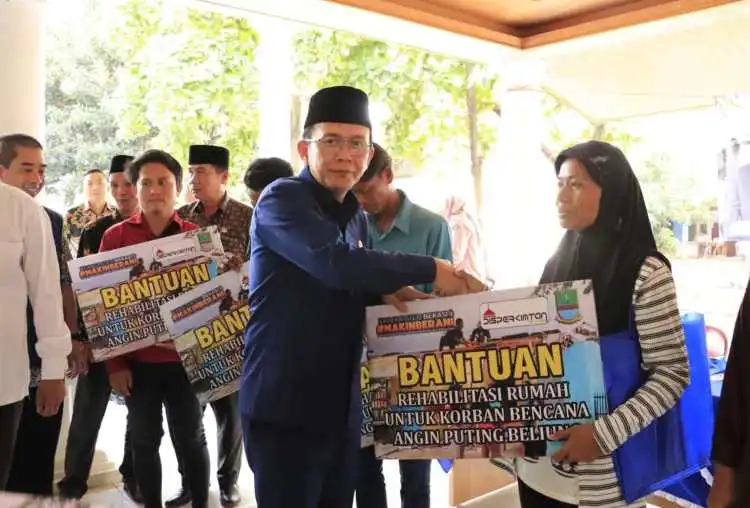 Pj Bupati Bekasi Dani Ramdan menyerahkan bantuan rehabilitasi rumah warga terdampak puting beliung di Kantor Desa Sumberjaya, Kecamatan Tambun Selatan.