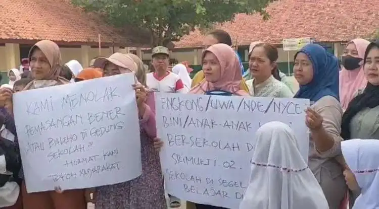 Sejumlah orang tua siswa membentangkan poster penolakan pemasangan spanduk klaim ahli waris yang telah terpasang di pagar SD Negeri Srimukti 02, Tambun Utara, Kabupaten Bekasi sejak Minggu 23 Juli 2023 kemarin.