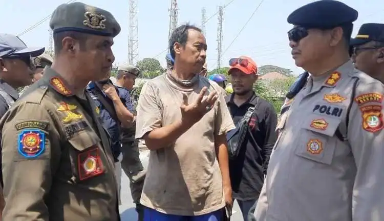 Kepala Satpol PP Kabupaten Bekasi, Surya Wijaya (kiri) saat menemui salah seorang pedagang di depan Pasar Tegal Danas yang lapaknya ditertibkan, Senin (27/09) pagi.