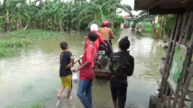 Sejumlah pemuda di Kampung Poncol, Desa Tanjungsari, Kecamatan Cikarang Utara, Kabupaten Bekasi meraup cuan dengan menawarkan jasa ojek gerobak saat banjir akibat luapan Kali Ulu.