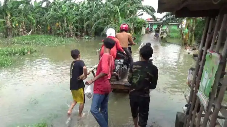 Sejumlah pemuda di Kampung Poncol, Desa Tanjungsari, Kecamatan Cikarang Utara, Kabupaten Bekasi meraup cuan dengan menawarkan jasa ojek gerobak saat banjir akibat luapan Kali Ulu.