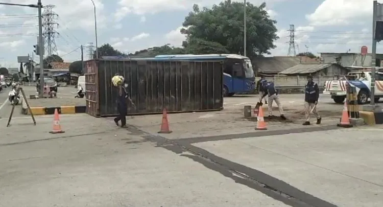 Sebuah truk kontainer bermuatan keramik terguling saat berbelok arah dari Jalan Teuku Umar menuju Gerbang Tol Telaga Asih, Cikarang Barat